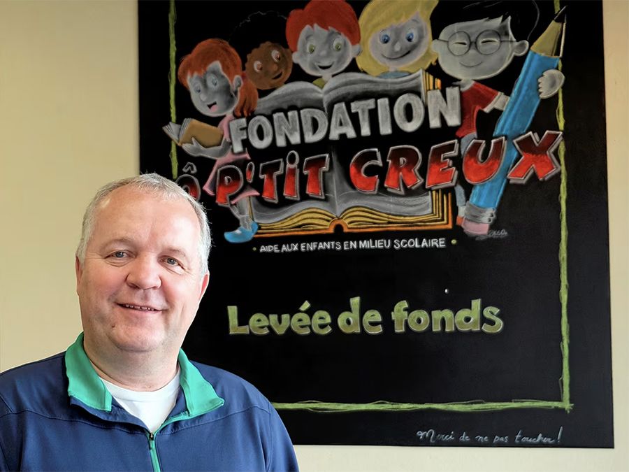 Photo de Patrick Viens devant une affiche de la Fondation Ô Petit Creux